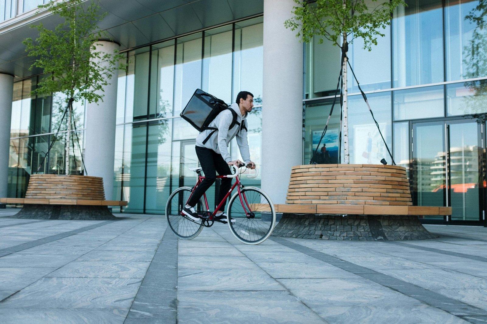 Bicycle courier delivering packages in an urban setting with modern architecture.