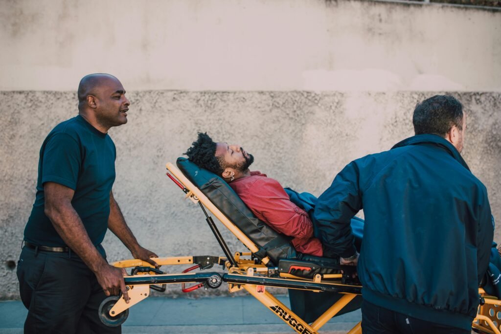 Two paramedics assist an unconscious patient on a stretcher outside. Medical emergency care concept.